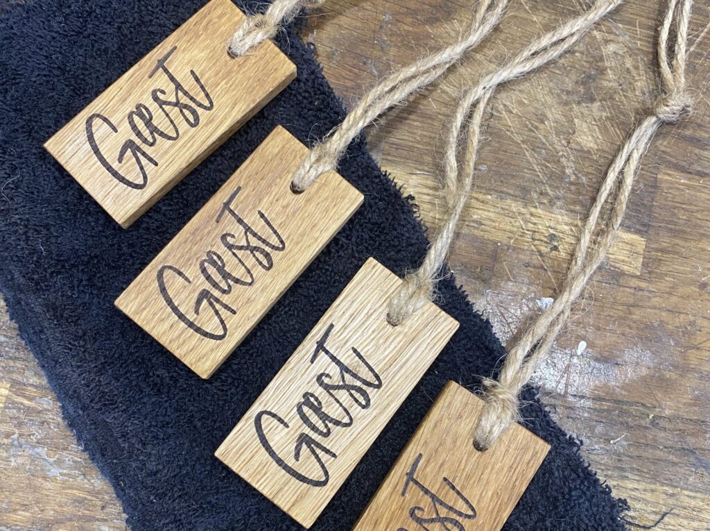 Træskillte med ordet GÆST udført i egetræ med jutegarn. Laserindgraveret og oliebehandlet.